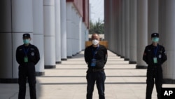 FILE - Security guards stand on duty at one of the temporary coronavirus hospitals during a visit by journalists in Wuhan, central China's Hubei province, April 9, 2020.