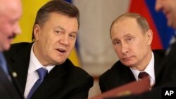 Russian President Vladimir Putin, right, and his Ukrainian counterpart Viktor Yanukovych, left, react after signing an agreement in Moscow, Dec. 17, 2013.