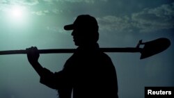 FILE - A drought-plagued Iranian farmer carries a shovel to his tomato field in Fars province.