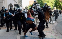 FILE - Police chase a man as they rush protesters to clear Lafayette Park and the area around it across from the White House for President Donald Trump to walk through for a photo opportunity in front of St. John's Episcopal Church, June 1, 2020.