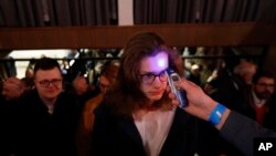 People have their temperature checked, as a precaution against the spread of the new coronavirus, as they enter the headquarters of the Ordinary People and Independent Personalities party to wait for the results of the general elections in Slovakia.
