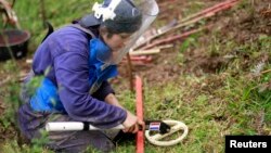 FILE - A woman practices searching for land mines during a training session involving mock land mines in El Retiro, Antioquia in Colombia, Jan. 23, 2013.