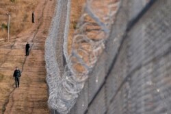 FILE - Bulgarian border police personnel stand next to a barbed wire wall fence erected on the Bulgaria-Turkey border near the town of Lesovo, on Sept. 14, 2016.