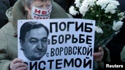 FILE - A woman holds a placard with a portrait of Sergei Magnitsky during an unauthorized rally in central Moscow December 15, 2012. The placard reads "Died fighting a system of thievery."