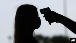 FILE - Amid concerns about the spread of COVID-19, a woman has her temperature checked in Arlington, Texas, June 1, 2020. 