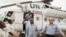 A member of the joint U.N. African Union Mission in Darfur (UNAMID), right, escorts three freed humanitarian workers out of a U.N. helicopter as they landed in El Fasher, North Darfur, Sudan, Saturday, July 19, 2014. The international peacekeeping mission