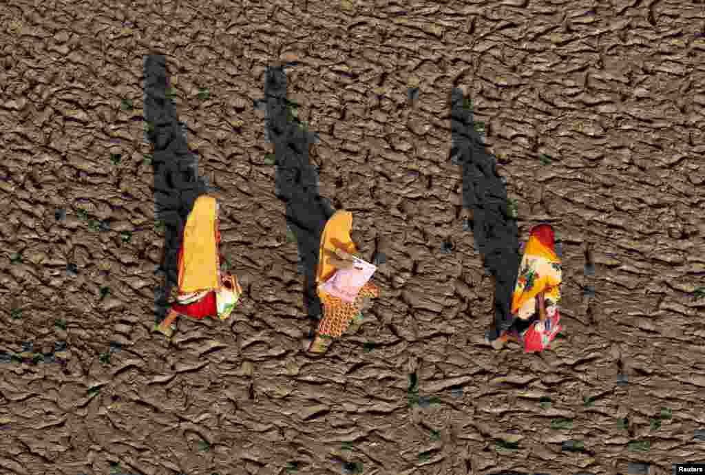 ស្រ្តី​បី​នាក់​ដើរ​លើ​ច្រាំង​ទន្លេ​ដែល​ពោរពេញ​ដោយ​ភក់​នៅ​ទន្លេ Ganges បន្ទាប់​ពី​បានធ្វើ​ការ​ជ្រមុជ​ទឹក​បរិសុទ្ធ​នៅ​ក្នុង​ទីក្រុង​ Allahabad ប្រទេស​ឥណ្ឌា។