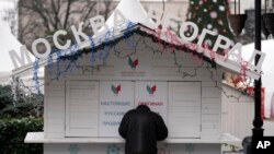 A man stands in front of a closed small shop called "Moscow - Belgrade", on the main pedestrian street in downtown Belgrade, Serbia, Jan. 16, 2023.