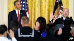President Barack Obama (L) watches as Deputy Homeland Security Secretary Alejandro Mayorkas administers the oath of allegiance during a naturalization ceremony for active duty service members and civilians, July 4, 2014, at the White House in Washington.