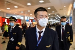 FILE - China Eastern Airlines flight crew wear protective masks on arrival at Sydney International Airport in Sydney, Australia, Jan. 23, 2020. (AAP Image/Joel Carrett/via Reuters)