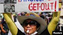 An anti-government protester holds a placard as she gathers with others during a rally at a major business district in Bangkok, Dec. 19, 2013.