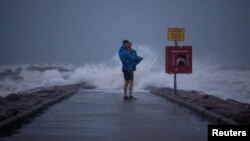 Warga setempat, John Smith menggendong putranya yang baru berusia 18 bulan, Owen, berdiri di tepi pantai Galveston, Texas, menjelang badai tropis Nicholas, 13 September 2021. (REUTERS/Adrees Latif/File Photo)
