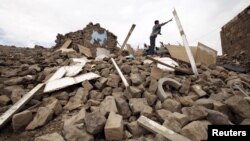 A youth throws a plank of wood away from a pile of rubble of a house destroyed during an airstrike carried out by the Saudi-led coalition in Faj Attan village, Sanaa, Yemen, May 7, 2015. 