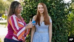 Annette Reynolds, left, puts the finishing touches on her daughter Amanda's hair as she poses for a photo in her prom gown outside their home in Largo. She will miss her high school graduation and senior prom due to the coronavirus outbreak. 
