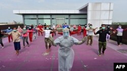 A gymnastics instructor wearing personal protective equipment (PPE) leads a morning exercise for patients of the COVID-19 coronavirus at a hotel designated to treat asymptomatic patients in Karawaci, Indonesia's Banten province, on October 5, 2020. 