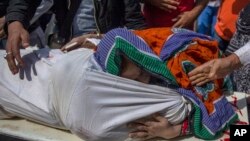 A Kashmiri woman hugs the body of a relative as it is carried on a stretcher outside a local hospital in Srinagar, Indian controlled Kashmir, Oct. 5, 2018. 