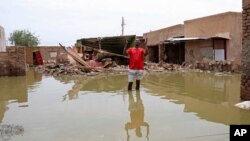FILE - A man gestures as he wades through a flooded road in the town of Salmaniya, about 35 km southwest of the capital, Khartoum, Sudan, Sept. 17, 2020.