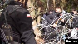 폴란드 정부가 8일 공개한 영상에서 경찰(왼쪽)과 이주자들이 벨라루스 국경 철조망을 사이에 두고 대치하고 있다.