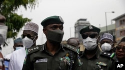Mohammed Adamu, Centre, Nigeria Inspector General of Police, visit a police station burnt down during a recent protest to end lockdown measures against COVID-19 in Lagos, Nigeria, Tuesday Nov. 3, 2020. (AP Photo/Sunday Alamba)