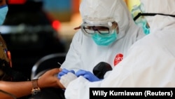 Petugas kesehatan yang mengenakan alat pelindung mengambil sampel darah untuk menguji seorang pria terhadap virus corona (COVID-19) di Bogor, Jawa Barat, 7 April 2020. (Foto: Reuters/Willy Kurniawan)