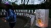 FILE - A volunteer helps setup lights in paper bags decorated with messages for the deceased during an Out of the Darkness Walk event organized by the Cincinnati Chapter of the American Foundation for Suicide Prevention in Sawyer Point park, Oct. 15, 2017, in Cincinnati.