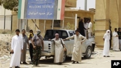 Armed Syrian rebels stand guard as refugees flee Syria at border crossing near Qaim, Iraq, July 25, 2012.