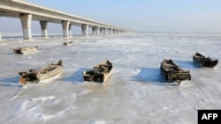 Row boats sit stuck in the ice of the frozen coastal waters of Jiaozhou Bay in Qingdao in eastern China's Shandong province, Jan. 25, 2016.