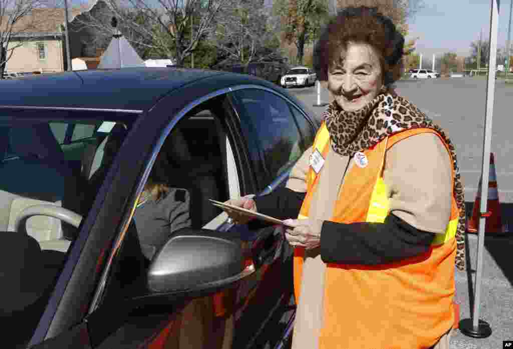 Observatrice des élections, Kathryn Ballen, à droite, vérifie un bulletin de vote qu&rsquo;elle prend des mains d&rsquo;un chauffeur qui s&rsquo;avance pour voter au parking de Harvard Gulch Recreation Center au Denver Sud, vendredi le 31 octobre 2014. (AP Photo / David Zalubowski) 