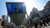 People pass by a TV screen broadcasting live President Xi Jinping's opening speech, outside a shopping mall in Beijing, April 26, 2019. 