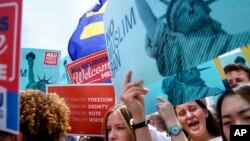 Protesters rally against the Supreme Court ruling upholding President Donald Trump's travel ban, outside the Supreme Court in Washington, June 26, 2018. 