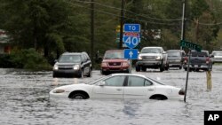 Mobil-mobil berusaha melewati jalanan yang tergenang banjir menuju Interstate 40 di Castle Hyane, North Carolina, pasca hantaman badai Florence yang menutup akses menuju Willmington, Noth Carolina, MInggu, 16 September 2018. 