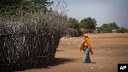 FILE - In this Dec. 19, 2017 photo, a Somali girl walks near a fence surrounding a hut at Dadaab refugee camp.