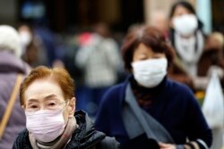 FILE - Pedestrians wear protective masks in Tokyo, Jan. 16, 2020.