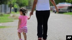 In this 2015 photo, in Sullivan City, Texas, a woman who is in the country illegally walks with her two-year-old daughter who was born in the in the United State but was denied a birth certificate.(AP Photo/Eric Gay)