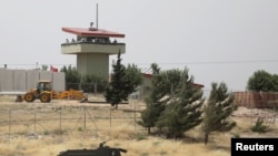 Beberapa tentara Turki berjaga di sebuah pos pengamatan di penyeberangan Atmeh di perbatasan Turki-Suriah, tampak dari Provinsi Idlib, Suriah, 31 Mei 2019. (Foto: Khalil Ashawi/Reuters)