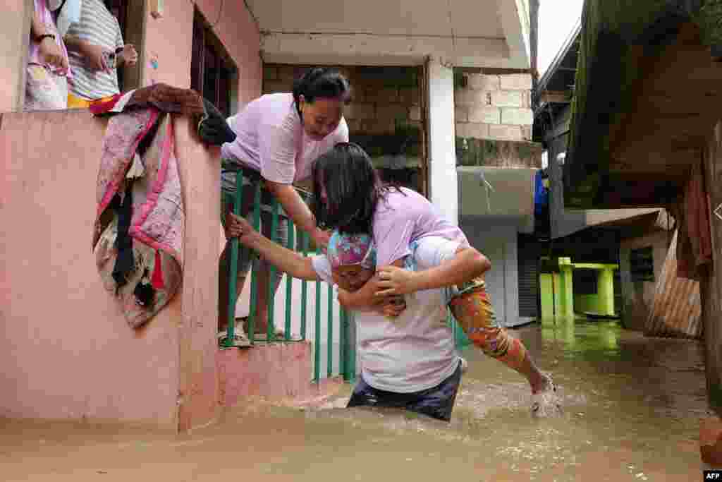 Residents evacuate from their flooded homes due to a swollen river caused by heavy rains and induced by Super Typhoon Man-yi in Tuguegarao City, Cagayan province.&nbsp;&nbsp;Floodwaters submerged houses and highways in the northern Philippines after water released from a dam following Typhoon Man-yi caused a major river to break its banks.