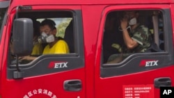 ក្រុម​អ្នក​ពន្លត់​អគ្គីភ័យ​ចិន​ពាក់​ម៉ាស​ នៅ​ខណៈ​ពួកគេ​រង់ចាំ​នៅ​ក្នុង​រថយន្ត​ជិត​កន្លែង​ដែល​មាន​ការ​ផ្ទុះ​នៅ​ក្រុង Tianjin ប្រទេស​ចិន។ 