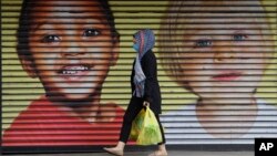 A woman wears a face mask to protect against the coronavirus as she passes a closed shop in London, Wednesday, April 29, 2020. (AP Photo/Kirsty Wigglesworth)