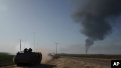 21일 가자지구에서 연기가 솟아오르는 가운데, 이스라엘군 장갑차가 접경지역에서 이동하고 있다.