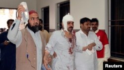 FILE - A man injured in an explosion in a Shi'ite mosque walks with relatives after receiving medical treatment at a hospital in Shikarpur, located in Pakistan's Sindh province, Jan. 30, 2015. 