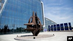 The NATO symbol in front of the glass facade of the new NATO headquarters in Brussels on Thursday, April 19, 2018.