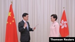 홍콩 정무 부총리로 임명된 존 리 홍콩 보안장관이 25일 캐리 람 행정장관 앞에서 취임선서를 하고 있다. 