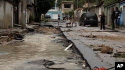 Neighbors look at the damage to a street after heavy rains caused flash floods in the Realengo neighborhood of Rio de Janeiro, Brazil, March 2, 2020. 