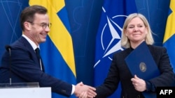 Švedski premijer Ulg Kristeršonn i liderka Socijaldemokrata Magdalena Anderšon razmenjuju dokumenta na konferenciji za novinare o prijemu Švedske u NATO, 11. marta 2024. (Foto: AFP/TT NEWS AGENCY/Lars Schroder)