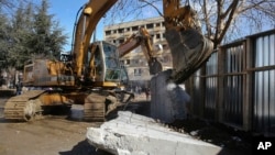 Buldoser meruntuhkan tembok beton di kota Mitrovica, Kosovo utara (5/2), yang telah memicu ketegangan antara Kosovo dan negara tetangga Serbia. (AP/Visar Kryeziu)