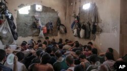 FILE -In this July 18, 2017, file photo, suspected Islamic State members sit inside a small room in a prison south of Mosul. 