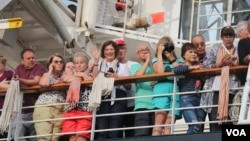 អ្នកដំណើរតាមនាវា Westerdam ឈរមើលការចាកចេញរបស់អ្នកដំណើរមួយចំនួន កាលពីព្រឹកថ្ងៃសុក្រ ទី១៤ ខែកុម្ភៈ ឆ្នាំ២០២០។ (ស៊ុន ណារិន/VOA)