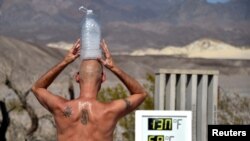 Steve Krofchik of Las Vegas keeps cool with a bottle of ice on his head as a thermometer reads 54.4 Celsius, (130 degrees Fahrenheit) with an error on the display causing the numbers to render incorrectly, in Death Valley, Calif., Aug. 17, 2020.