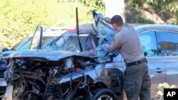 Seorang petugas penegak hukum memeriksa kendaraan yang rusak menyusul kecelakaan terguling yang melibatkan pegolf Tiger Woods, Selasa, 23 Februari 2021, di pinggiran Rancho Palos Verdes, Los Angeles. (Foto: AP)