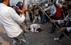 People supporting the new citizenship law beat a Muslim man during a clash with those opposing the law in New Delhi, India, Feb. 24, 2020.